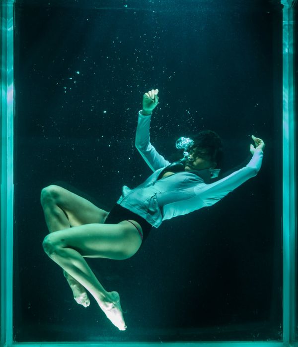 Woman in a dynamic movement pose against a deep blue background.